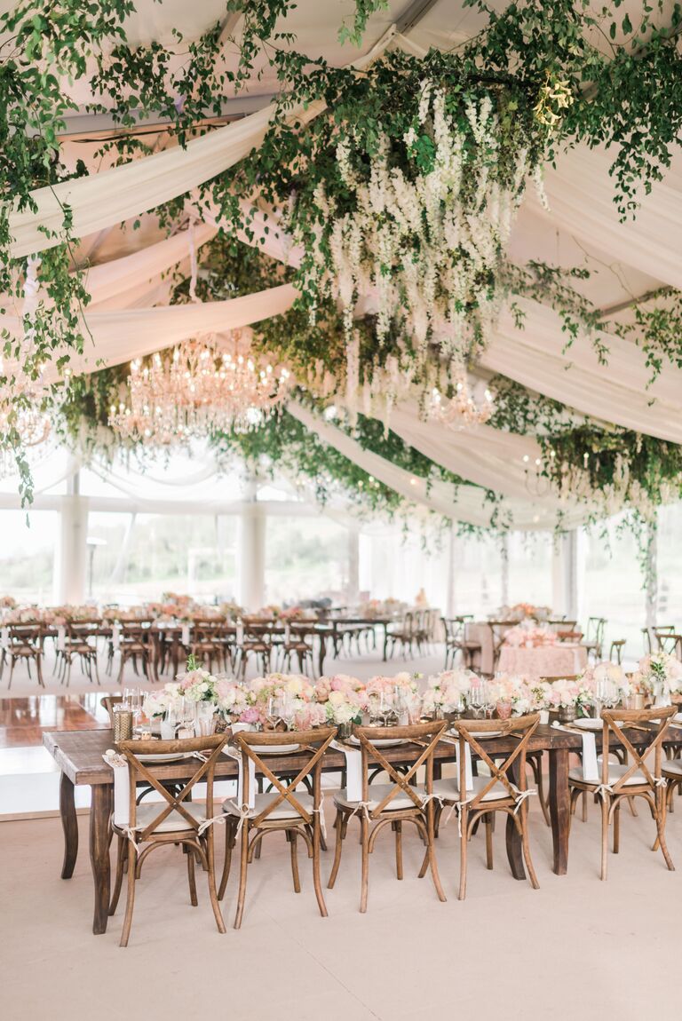 Romantic reception with greenery and chandeliers decorating the ceiling