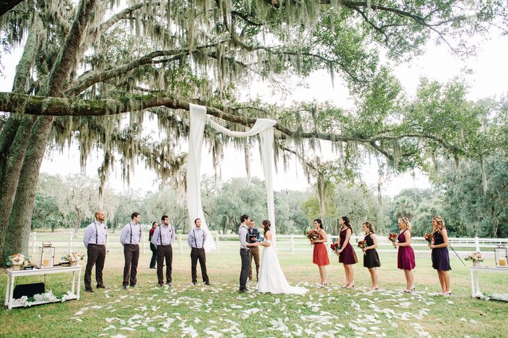 Their aisle decor couldn't have been more chic. Ivory skeleton magnolia leaves cascaded down the aisle and filled their ceremony space by an ivory fabric wedding arch.