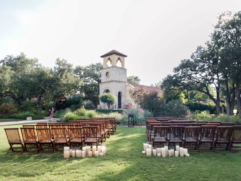 An outdoor, Italian-inspired ceremony site with wooden chairs and candles.