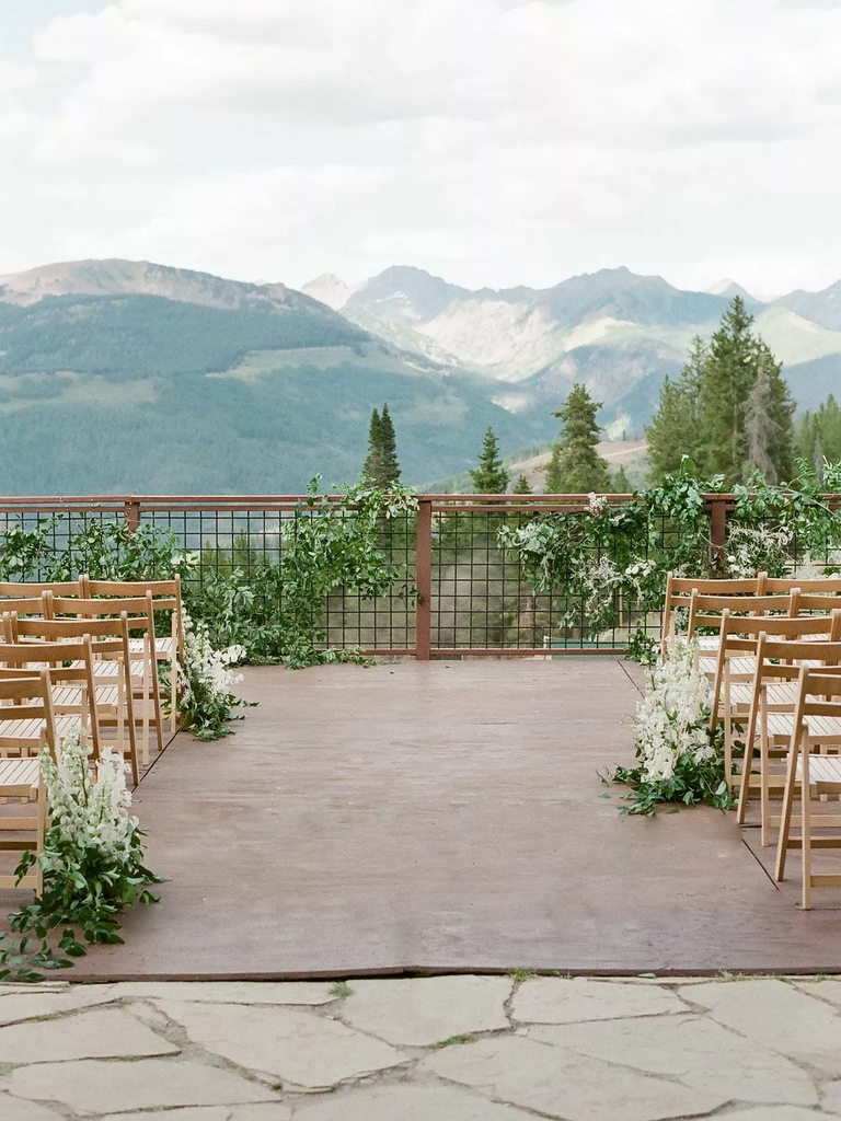 A vibrant outdoor wedding terrace, complete with wooden folding chairs and white floral arrangements.