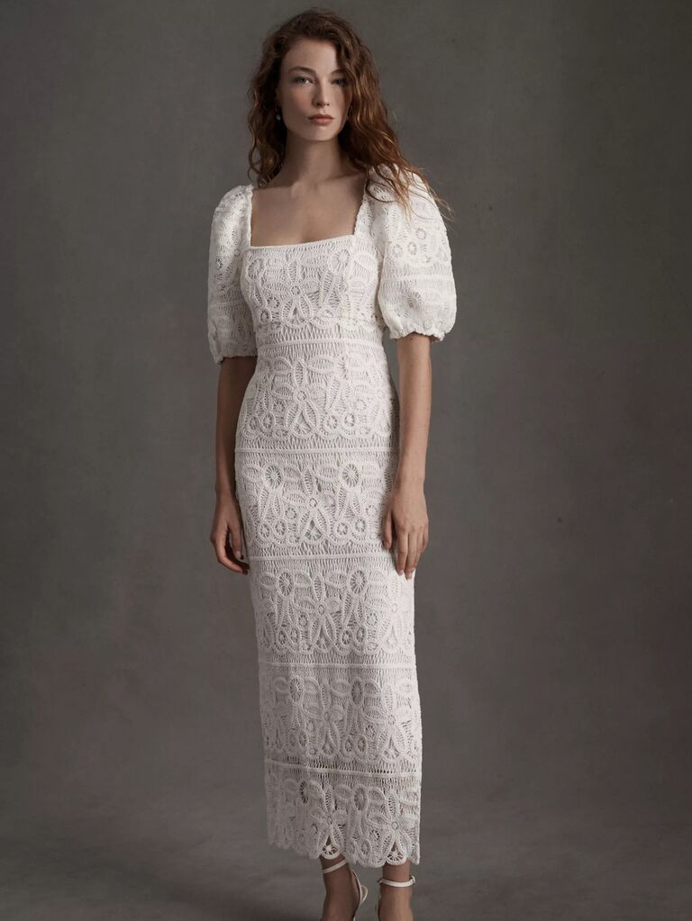 Model wears a bohemian white dress with lacy detailing. 