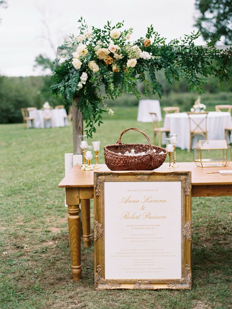 elegant wedding gift table with gold framed welcome sign, glass card box and wedding favors in woven basket