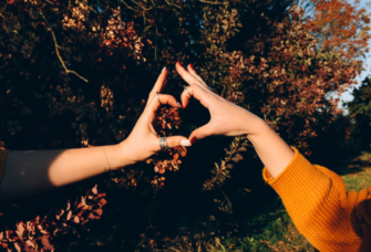 Couple making heart with hands during fall