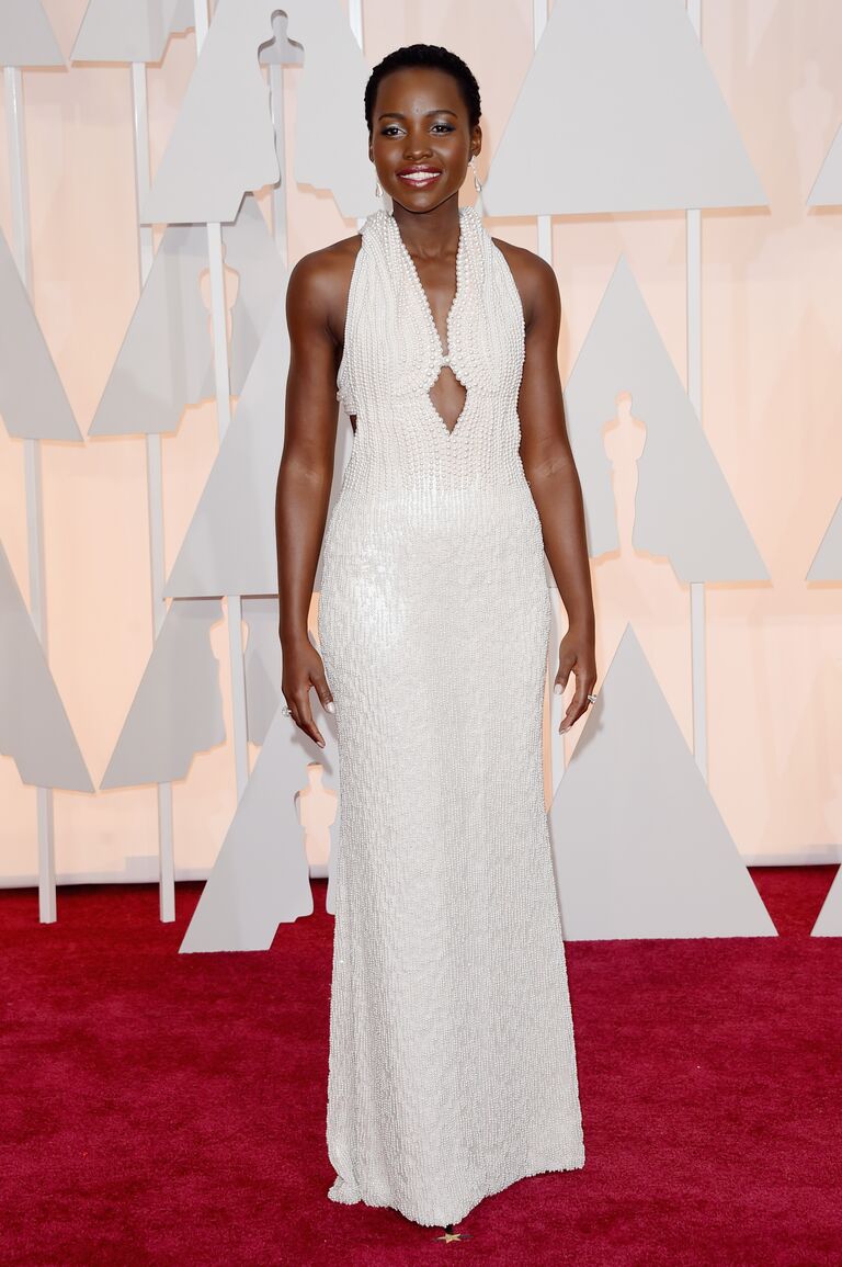 Lupita Nyong'o wearing a white pearl-covered dress on the Oscars red carpet