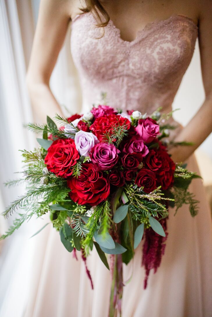 Her bouquet was fit for an enchanted garden. Designed by Judy Suarez, their florist, pink and red roses and red peonies were surrounded by lush greenery. Eucalyptus and leaves from an evergreen tree brought in their natural flair.