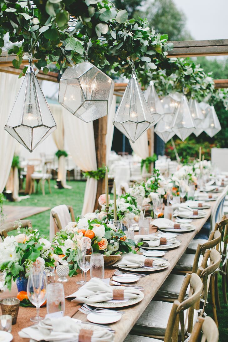 At the outdoor garden reception at Rancho Valencia in Rancho Santa Fe, California, chic geometric chandeliers were strung over the long banquet tables to add light and cozy ambiance.