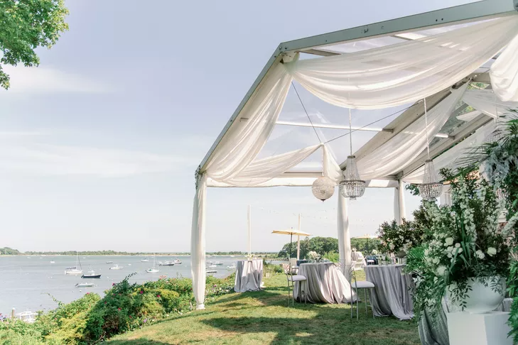 Open-air tent with chandeliers at waterfront reception