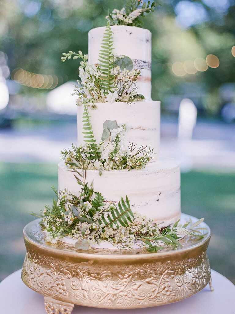 Three-tier wedding cake decorated with ferns and baby's breath