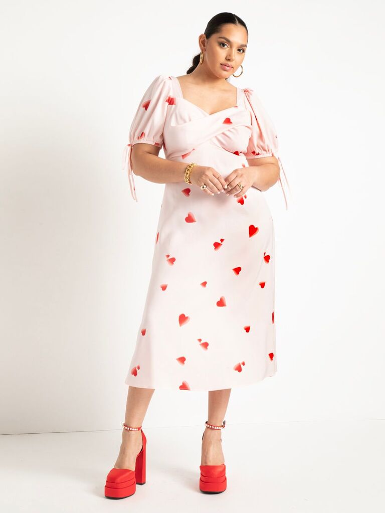 Model wears a silk dress with hearts printed on the fabric. 