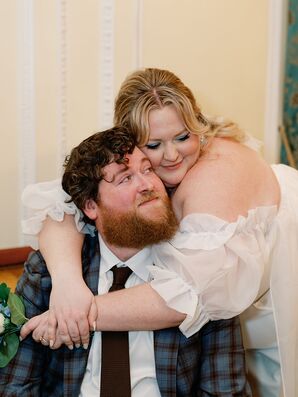 Bride With Curtain Bangs and Puff Sleeves Hugs Groom in Blue Suit