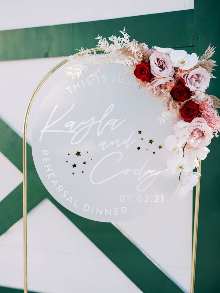 Circular Rehearsal Dinner Welcome Sign With Stars and Red and Pink Flowers