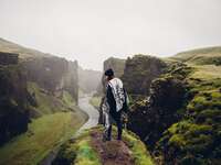 woman standing on green cliff in iceland admiring beautiful mountain scenery