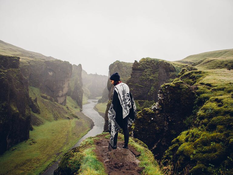 woman standing on green cliff in iceland admiring beautiful mountain scenery