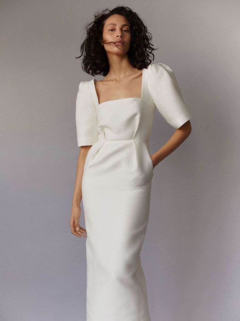 Model wears a white structured dress. 