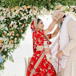 Bride placing mala around groom's neck at Hindu ceremony.