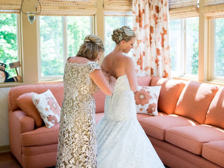 Mother of the bride helps her daughter into her wedding dress. 