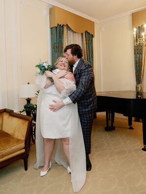 Groom in Blue Plaid Suit Hugs and Kisses Bride in Minidress and Bouquet