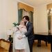 Groom in Blue Plaid Suit Hugs and Kisses Bride in Minidress and Bouquet
