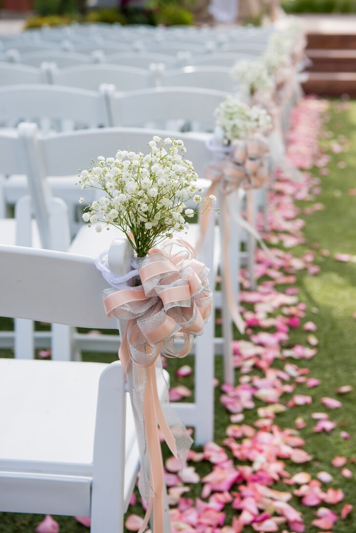 Pink rose petals were scattered down the sides of the aisle, giant pink bows and baby’s breath were tied on aisle seats, and bouquets were placed on the altar.