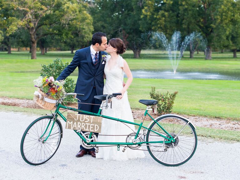 Bride and groom standing next to a tandem bike.