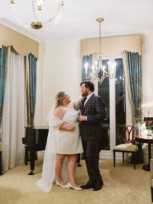 Bride in a Minidress and Groom in Checkered Suit With Champagne in Hotel Suite