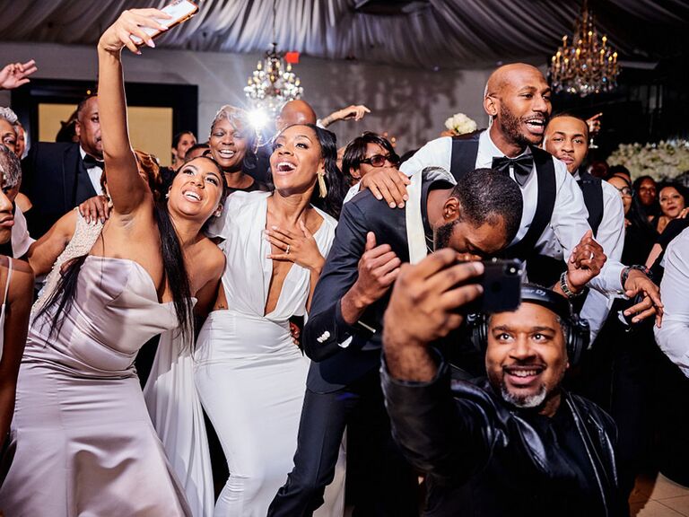 Wedding guest taking selfie with bride and groom during wedding reception