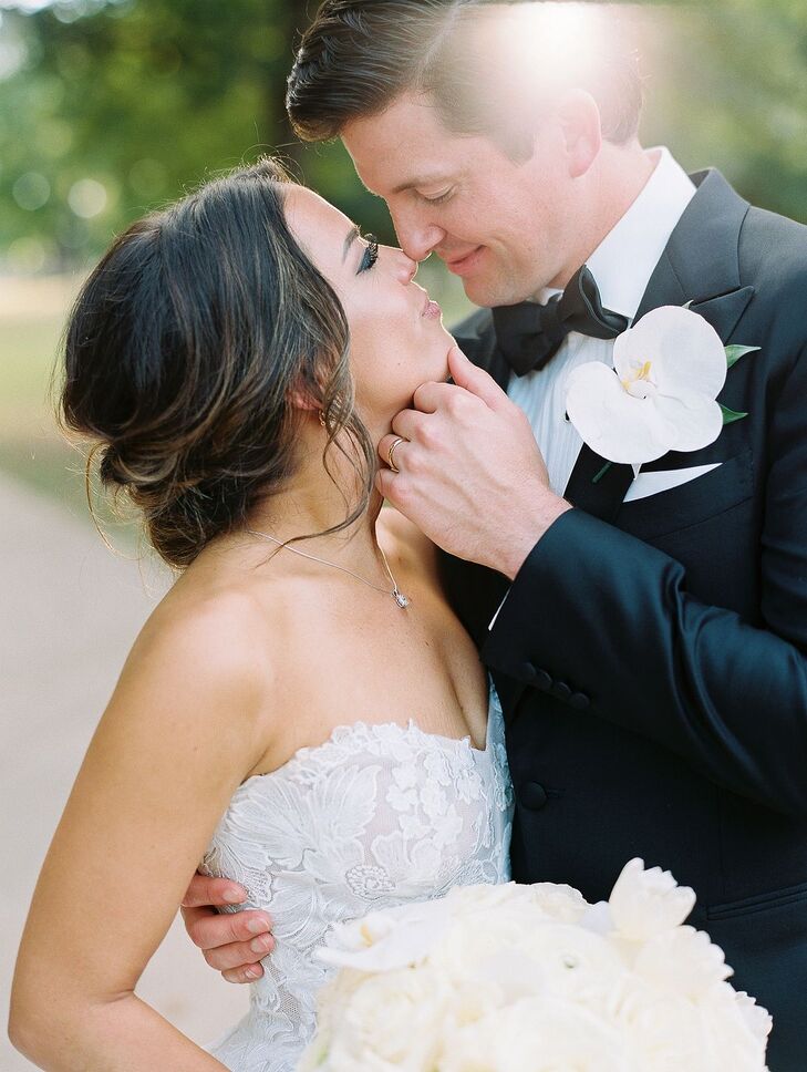 Bride in Sweetheart Dress and Low Bun Embraces Groom With Orchid Boutonniere