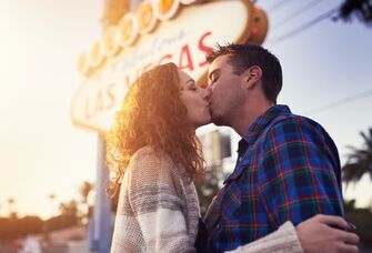 A couple kiss outside of the famous Las Vegas sign