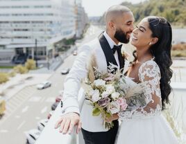 Bride and groom laughing on a rooftop overlooking a city street
