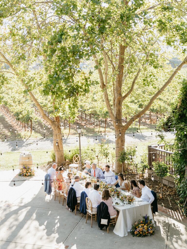 Outdoor dining table under the canopy of lush trees. 