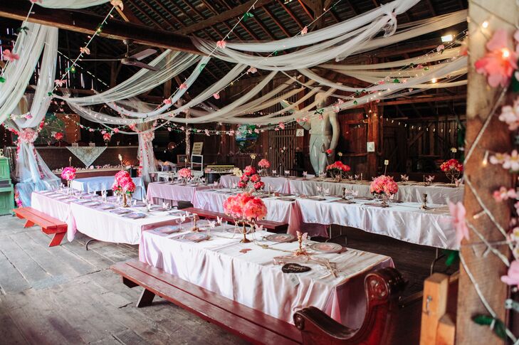 The reception, which took place in the barn at the museum, featured farmhouse-style tables with picnic bench seating. White drapes and string lights with flowers were hung from the exposed beams and wrapped around the wooden posts.