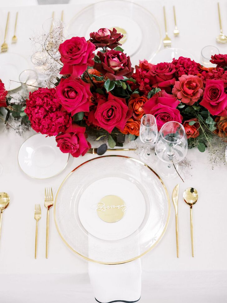 White and Gold Place Setting With Mirrored Gold Name Cards and Red Flower Centerpiece