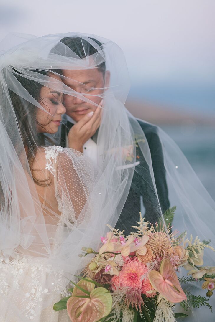 Bride and Groom Pose Under Bride's Long Veil With Colorful Tropical Bouquet