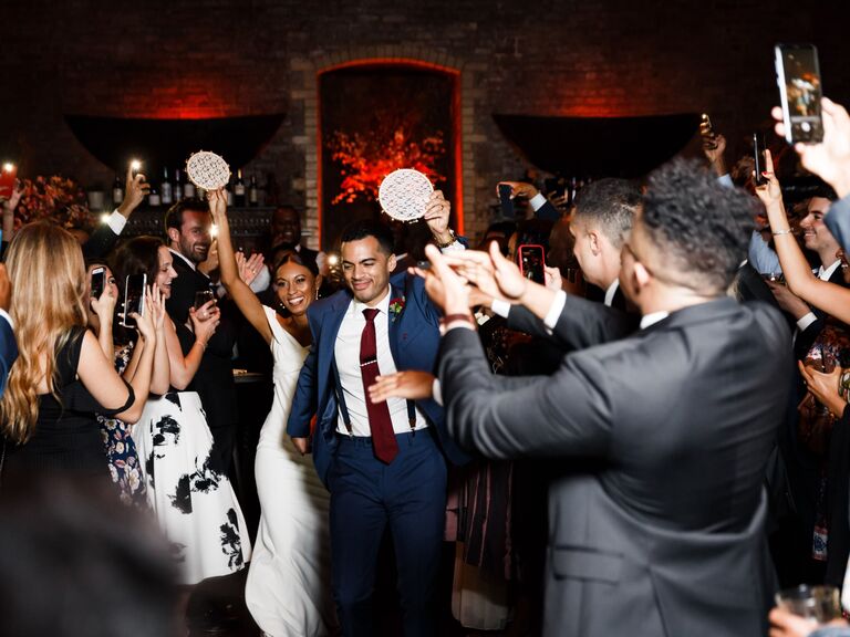 Bride and groom shake lace tambourines at reception exit. 