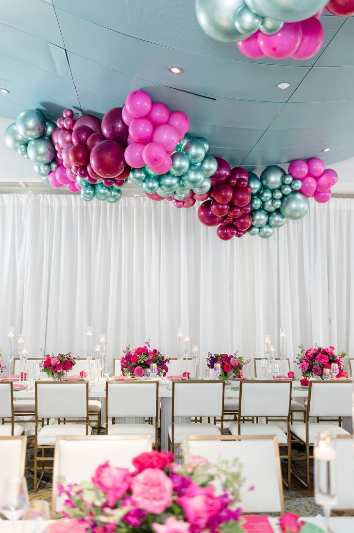 Long, White Tables With Bright Centerpieces Under a Balloon Structure on the Ceiling
