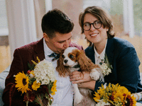 Couple smiling and posing with their Cavalier King Charles Spaniel. 