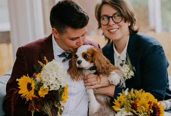 Couple smiling and posing with their Cavalier King Charles Spaniel. 