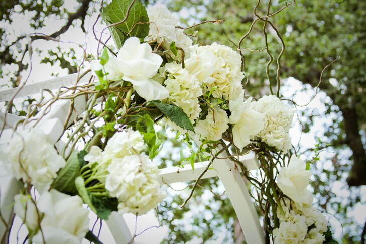 Brandy and John were married at the white wooden wedding arch, adorned with ivory  hydrangeas and roses mixed with green leaves and branches.