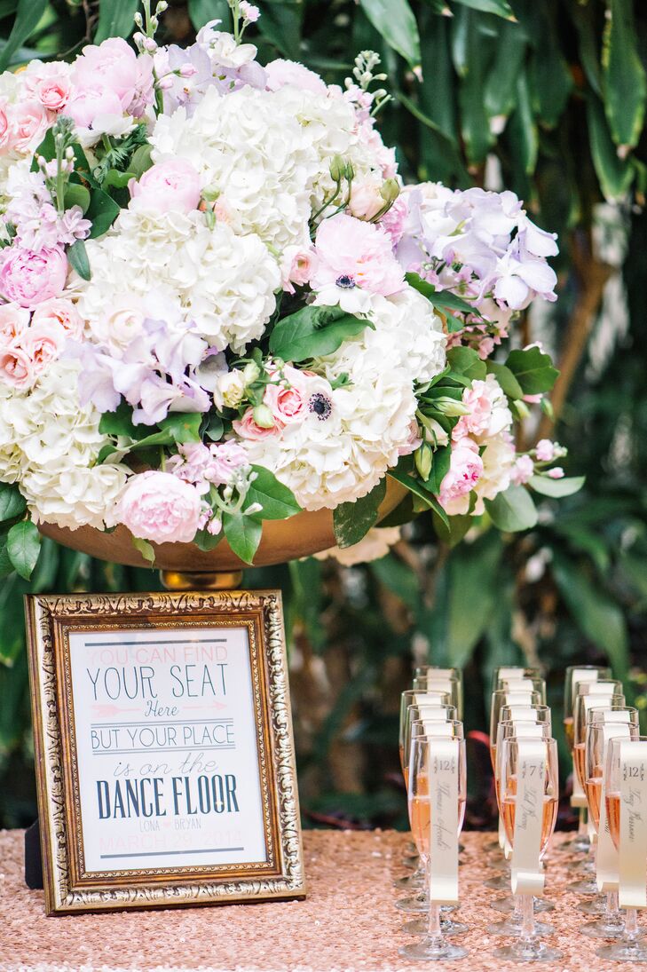 The escort card table was decorated with a sign that read, “You can find your seat here, but your place is on the dance floor”, and a gold vase full of hydrangea, ranunculus, anemones, peonies and roses.