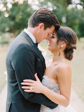 Bride in Strapless Dress and Low Bun Hairstyle Hugs Groom in Tuxedo