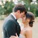 Bride in Strapless Dress and Low Bun Hairstyle Hugs Groom in Tuxedo