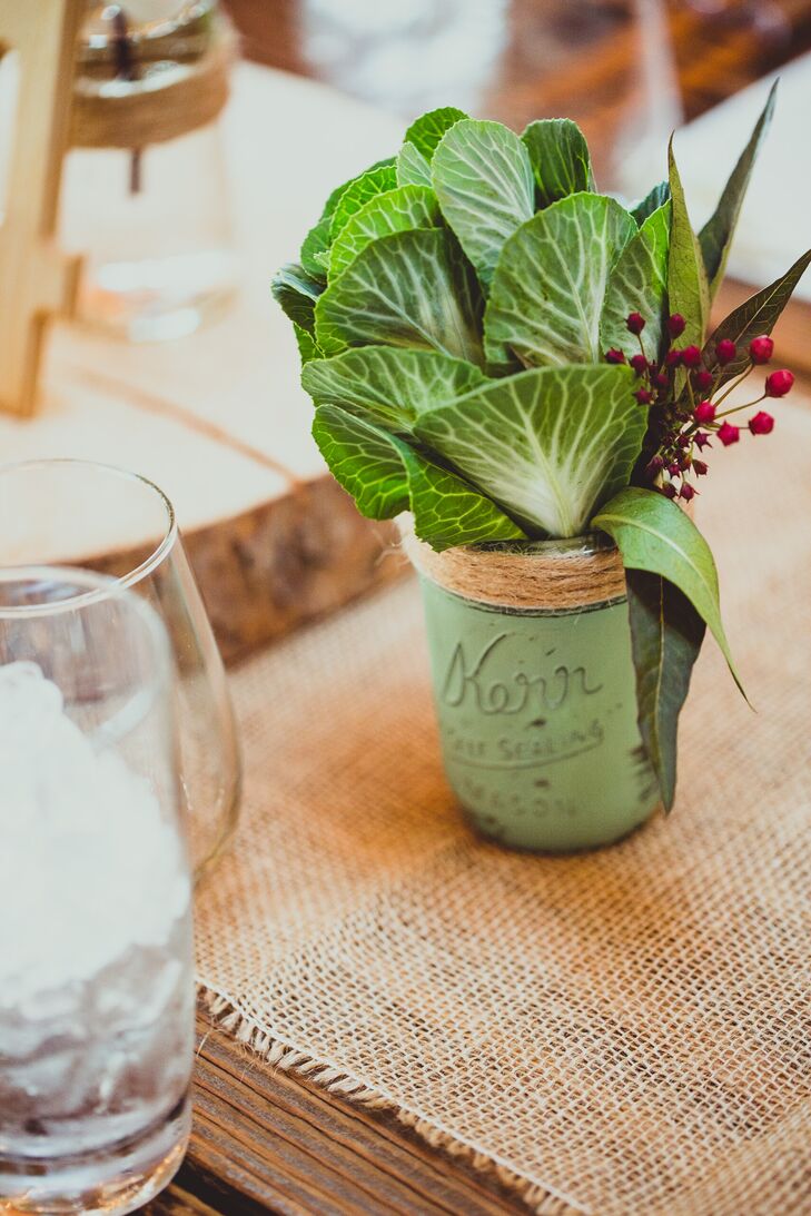 Green plant leaves accented with berries were placed in green painted mason jars for centerpieces.