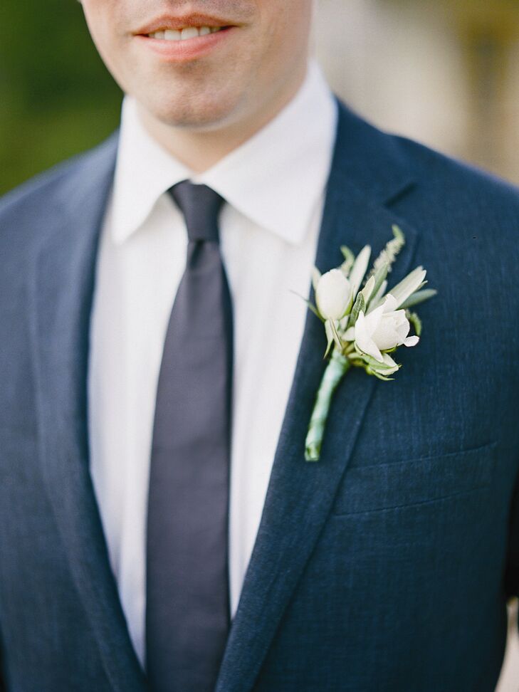 A green and white boutonniere of rose buds, olive leaves, rosemary and viburnum berries popped against Brandon's navy lapel.
