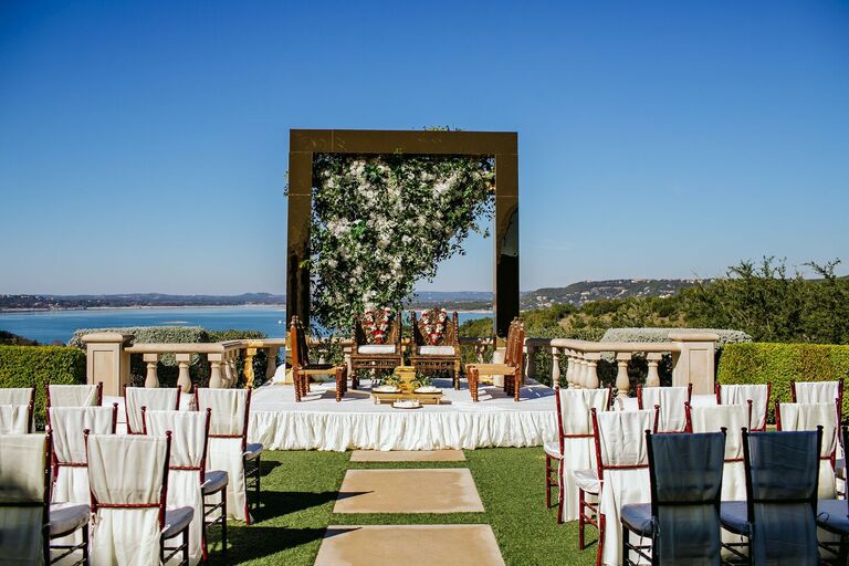 Outdoor wedding ceremony with mirrored arch and chairs with white linen covers