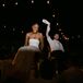 Bride and Groom Under String Lights Lifted Up in Chairs During Reception