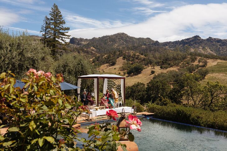 A lightly adorned mandap and an interfaith Indian wedding ceremony with drapery and strings of marigolds at a private vineyard residence in California.