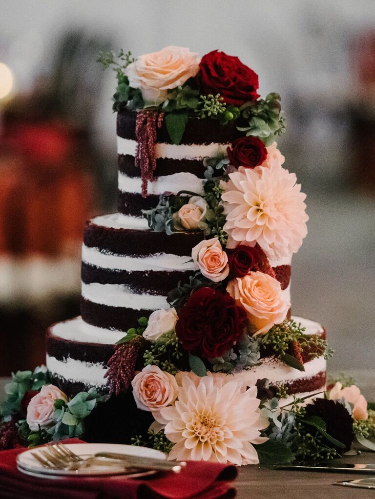 chocolate naked wedding cake decorated with pink dahlias, red roses and burgundy amaranthus
