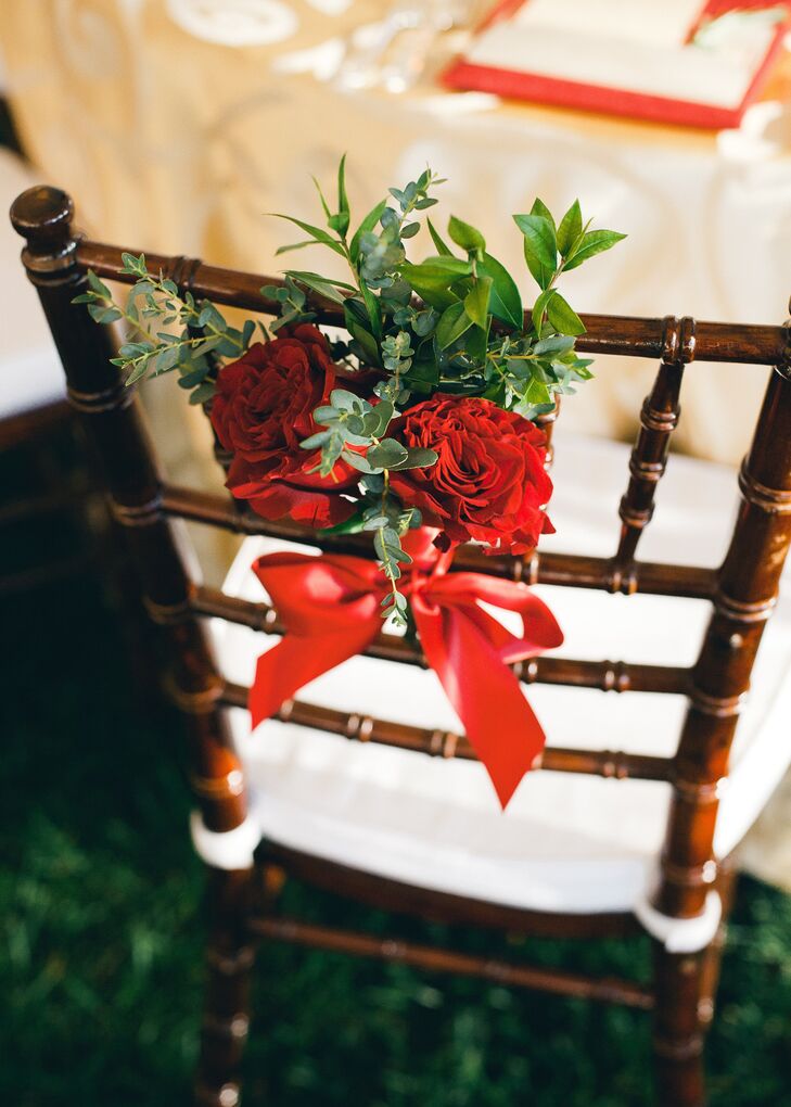 Fresh bunches of greenery and dark red roses were tied to the back of each reception chair with a simple red bow.