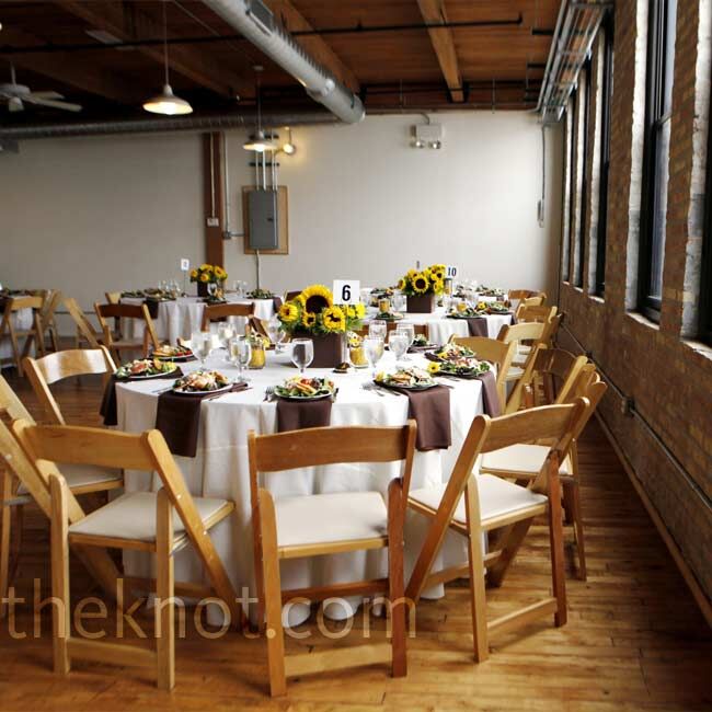 The potted sunflowers from the ceremony doubled as table centerpieces in the rustic reception room.