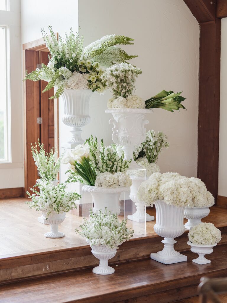 assorted white urn vases with white hydrangeas, calla lilies, and long stem flowers